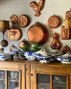 an old china cabinet with plates and other items on it's wall above the hutch