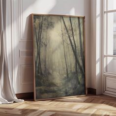 a painting is sitting on the floor in front of an open window with white curtains