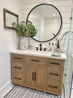 a bathroom with a sink, mirror and plants in the vase on the counter top