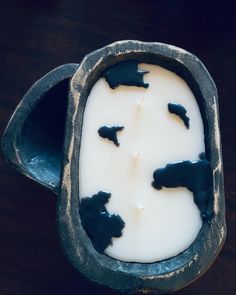 a bowl filled with white and black liquid on top of a wooden table next to a spoon