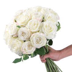 a bouquet of white roses being held by a person's hand on a white background