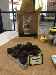 a table topped with chocolate covered donuts next to a sign that says tractor tires