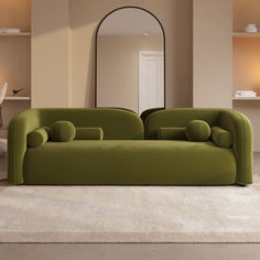 a green couch sitting on top of a white rug in a living room next to a mirror