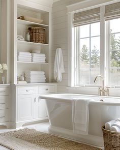 a bathroom with white walls and flooring has a large bathtub in the center