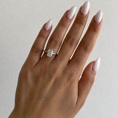 a woman's hand with white manicured nails and a diamond ring