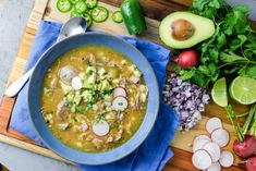 a blue bowl filled with soup next to sliced radishes and avocado