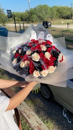 a woman holding a bouquet of roses in front of a car