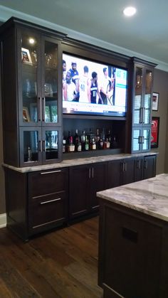 a home bar with an entertainment center and marble counter tops in front of the tv