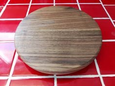 a wooden cutting board sitting on top of a red tile floor