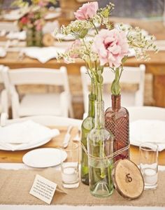 the table is set with wine bottles and flowers in vases, plates and napkins