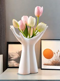 a vase filled with pink and white tulips on top of a table