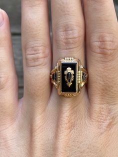 a person's hand with a gold and black square ring on top of it