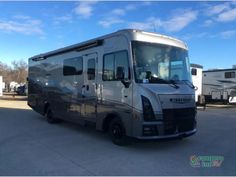 an rv parked in a parking lot next to another vehicle and trailer on the other side