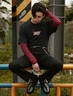 a young man sitting on top of a blue and yellow pole with his hands in his hair