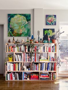 a bookshelf filled with lots of books in a living room next to a window