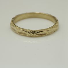 an antique yellow gold wedding ring with engraved details on the sides, set against a plain white background