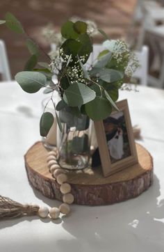 there is a vase with flowers in it on top of a wooden slice at the table