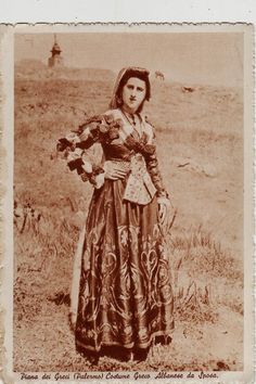 an old photo of a woman in a long dress holding a teddy bear and posing for the camera