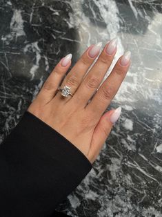 a woman's hand with white manicured nails and a ring on her finger