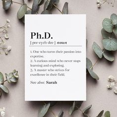 a sheet of paper with the words ph d on it next to some leaves and flowers