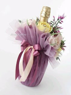 a bottle of champagne and some flowers in a purple basket on a white tablecloth