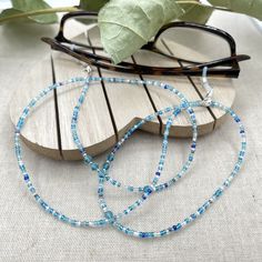 Dainty and bohemian eyeglass necklace chain made with tiny Preciosa Czech crystal seed beads in blue tones and small round faceted cubic zirconia crystals.   Paired with beautiful blue cz gems, this handmade eyeglass chain will definitely create a unique look. This eyeglass lanyard is made on strong quality beading wire with silver plated wire guardians that protect the eyeglass holder grips. The necklace is ended with spring clasps that hold the eyeglass grips and they can be easily removed to Adjustable Glass Beaded Necklaces With Tiny Beads, Adjustable Glass Beaded Necklace With Tiny Beads, Adjustable Tiny Beaded Glass Necklaces, Adjustable Tiny Beaded Glass Necklace, Blue Beaded Glass Glasses Chains, Adjustable Glass Necklaces With Tiny Beads, Adjustable Blue Glasses Chains With Colorful Beads, Adjustable Glass Necklace With Tiny Beads, Adjustable Clear Beaded Necklace For Gifts