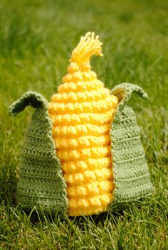 two crocheted corn cobs sitting in the grass