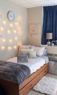 a bed room with a laptop on top of it next to a wall mounted clock