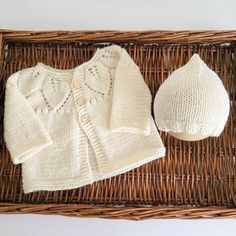 a knitted sweater and hat sitting on top of a wicker basket next to a stuffed animal