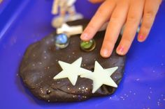 a child's hand on top of a rock with white stars and other decorations