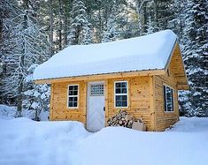 a small wooden cabin in the woods covered with snow