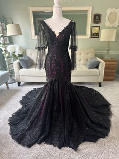 a black evening gown on display in a room with a couch and chair behind it