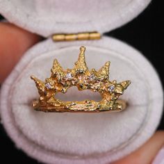 a close up of a gold crown ring in a white box with a black background