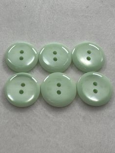 six green buttons sitting on top of a white surface