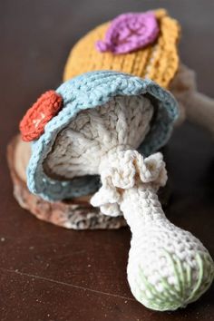 two crocheted hats sitting on top of a piece of wood