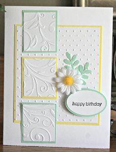 a birthday card with white and yellow flowers on the front, sitting on a table