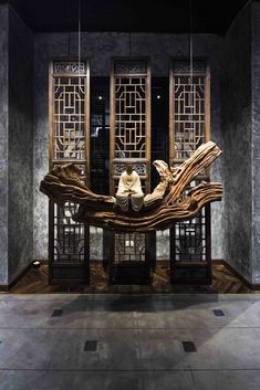 a wooden bench sitting on top of a floor next to two windows with carved wood frames