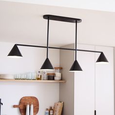 three lights hanging from the ceiling above a counter top in a room with white walls