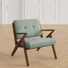 a green chair sitting on top of a hard wood floor next to a white wall