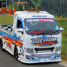 a white truck driving down a street next to grass