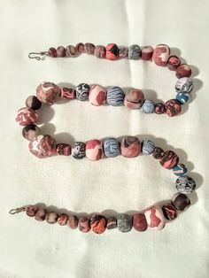 This necklace is made of handmade springtime colored polymer beads. Some of these beads have gold sparkles in them. Lots of pink, blue, gray etc. This necklace comes with a gold toned wire hook. All strung on nylon string. It is 19 - 3/4 inches in length. I accept returns within 30 days guarantee and I will refund you back. Artisan Pink Necklace With Colorful Beads, Round Beaded Polymer Clay Jewelry, Large Polymer Clay Bead Jewelry, Polymer Clay Jewelry With Large Round Beads, Bohemian Polymer Clay Round Beads Jewelry, Bohemian Beaded Polymer Clay Necklaces, Blue Polymer Clay Jewelry With Colorful Beads, Beaded Bohemian Polymer Clay Necklaces, Unique Pink Beads For Jewelry Making