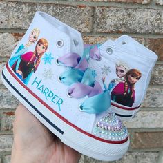 These are white Converse high tops with the images shown as well as a name and  snowflakes in glittery colors just like the photos. The toes have blue/white/silver/lavender bling on them. Bling Toes, White Converse High Tops, Elsa Shoes, Frozen Shoes, Bling Sneakers, White High Top Converse, Anna And Elsa, Kids Birthday Themes, White Converse