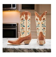 Idyllwind Women's Rosie Western Boots (Medium Sizes). This stylish boot features a tan leather upper with a snip toe design, making it perfect for dressing up or adding a touch of cowboy style to your everyday look. The pull tabs make it easy to slip on and off, while the leather upper provides a comfortable and breathable fit. The floral embroidery and inlay design on the shaft add a touch of whimsy and charm, making this boot a standout piece. The western heel gives the boot a classic cowboy s Fitted Cream Boots For Rodeo, Western Cream Ankle Boots, Western Style Cream Ankle Boots, Western Fall Boots With Heel Tab, Western Cream Boots For Ranch, Beige Leather Heeled Boots With Snip Toe, Cream Snip Toe Boots For Rodeo, Cream Snip Toe Boots For Fall, Cream Snip Toe Boots For Ranch