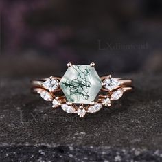 a close up of a ring on a rock with an aqua green stone surrounded by white diamonds