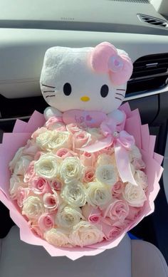 a hello kitty stuffed animal sitting on top of a bouquet of pink and white roses