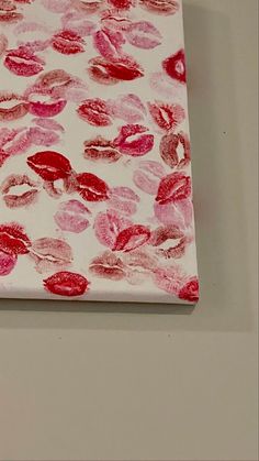 a piece of paper with pink and red lipstick prints on it, sitting on a white surface