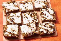 several squares of granola and white icing sitting on a cutting board next to each other