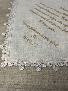 a close up of a table cloth with white lace on it and the words in brown ink