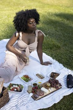 a woman is sitting on the grass with food