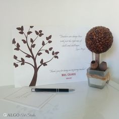 there is a card with a tree on it next to a pen and inkwell